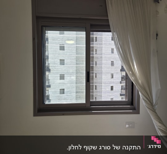 חלון עם וילון לבן בחדר מואר